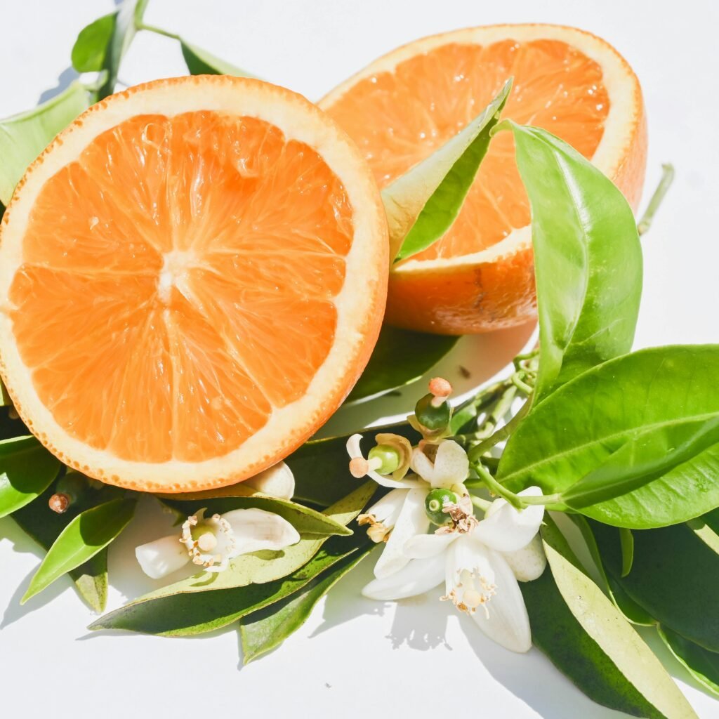 pexels-photo-18815185-18815185 Bright orange halves and blossoms on white, symbolizing freshness.